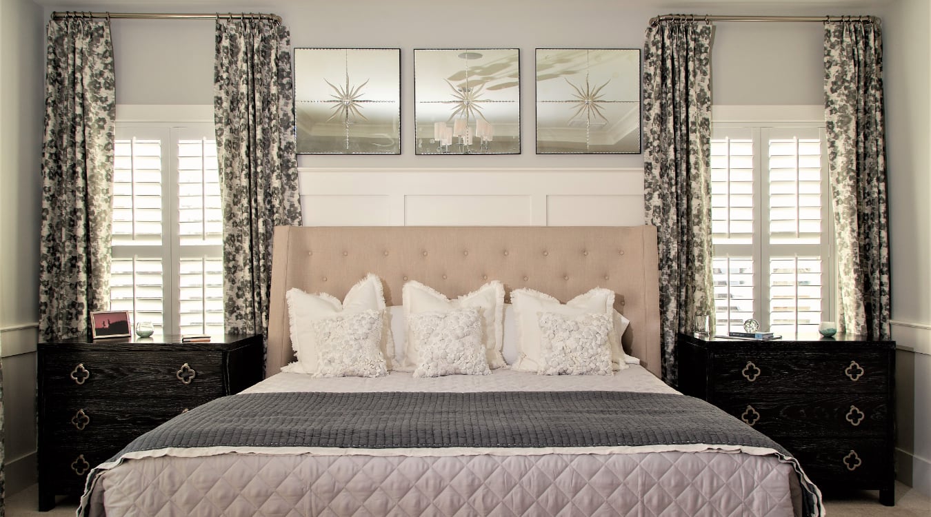 Layering plantation shutters with curtains can help create a cohesive look. Plantation shutters in a bedroom